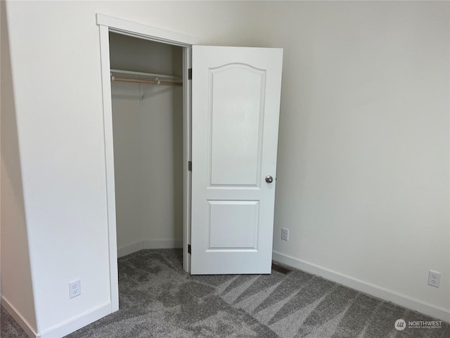 unfurnished bedroom with a closet and dark colored carpet