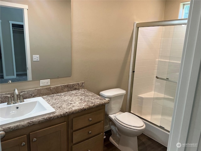 bathroom featuring hardwood / wood-style flooring, vanity, an enclosed shower, and toilet