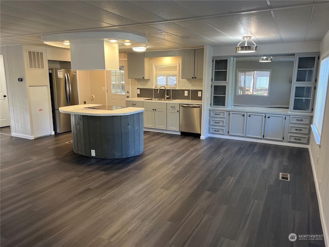 kitchen with a kitchen island, appliances with stainless steel finishes, sink, white cabinets, and decorative backsplash