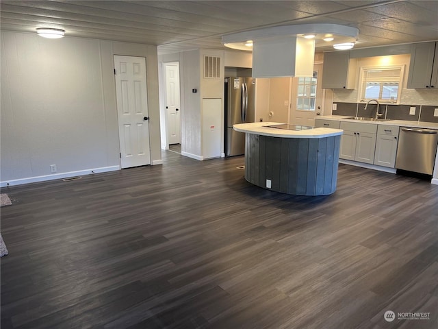 kitchen with appliances with stainless steel finishes, dark hardwood / wood-style floors, sink, and a kitchen island