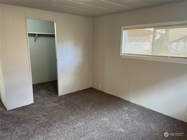 unfurnished bedroom with dark colored carpet and a closet