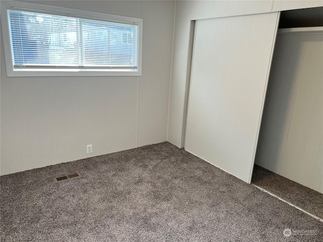 unfurnished bedroom featuring dark colored carpet and a closet