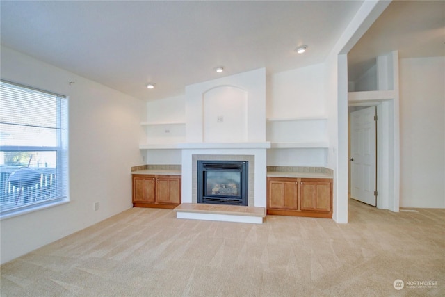 unfurnished living room featuring light carpet, a fireplace, and recessed lighting