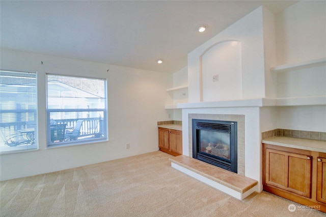 unfurnished living room with recessed lighting, light carpet, and a fireplace