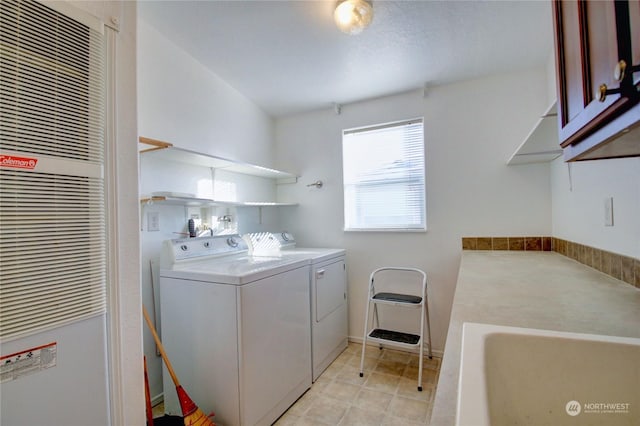 clothes washing area with cabinets, washing machine and dryer, and sink