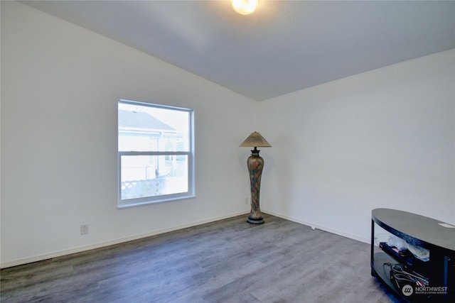 unfurnished room with vaulted ceiling, wood finished floors, and baseboards