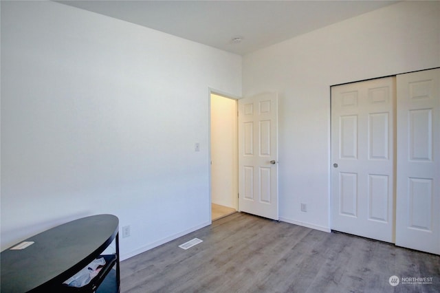 unfurnished bedroom with light wood finished floors, baseboards, visible vents, and a closet