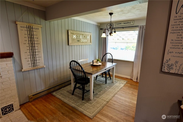 dining space with a baseboard heating unit, light hardwood / wood-style floors, and a chandelier