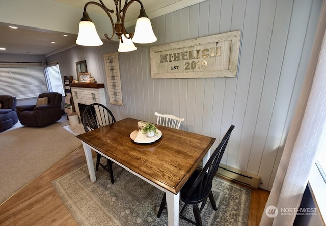 dining space featuring hardwood / wood-style flooring, a baseboard radiator, a chandelier, and a fireplace