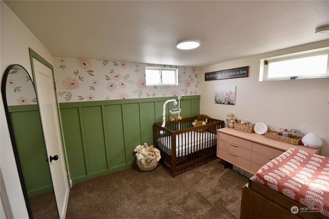 bedroom with multiple windows, a crib, and dark colored carpet