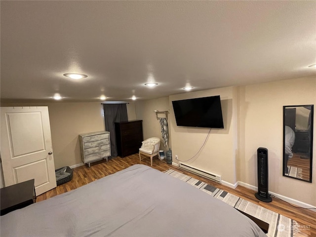 bedroom with a baseboard heating unit and dark hardwood / wood-style flooring