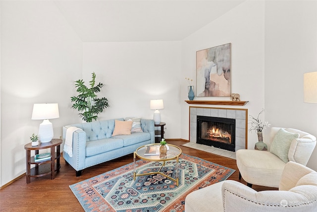 living room with lofted ceiling, hardwood / wood-style flooring, and a tiled fireplace