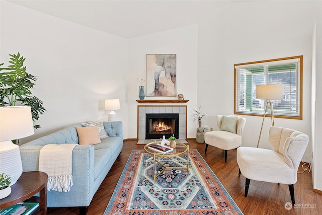 living room featuring lofted ceiling, dark hardwood / wood-style flooring, and a tiled fireplace