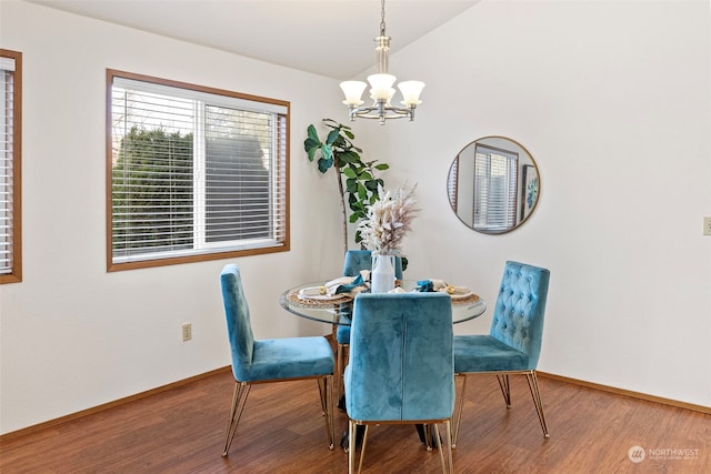 dining area with lofted ceiling, hardwood / wood-style floors, and an inviting chandelier