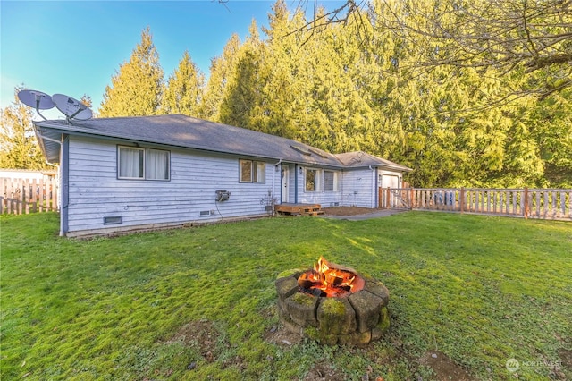 rear view of house with a yard and a fire pit