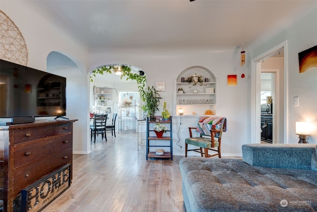 living room with built in shelves and light wood-type flooring