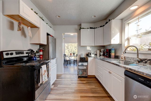 kitchen featuring sink, a textured ceiling, stainless steel appliances, light hardwood / wood-style floors, and white cabinets