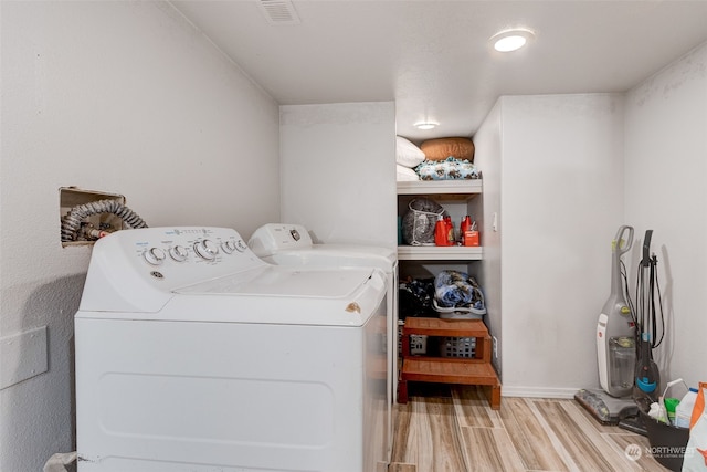 washroom with washing machine and dryer and light hardwood / wood-style flooring