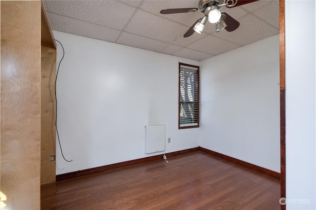 spare room featuring dark wood-type flooring, radiator heating unit, a drop ceiling, and ceiling fan