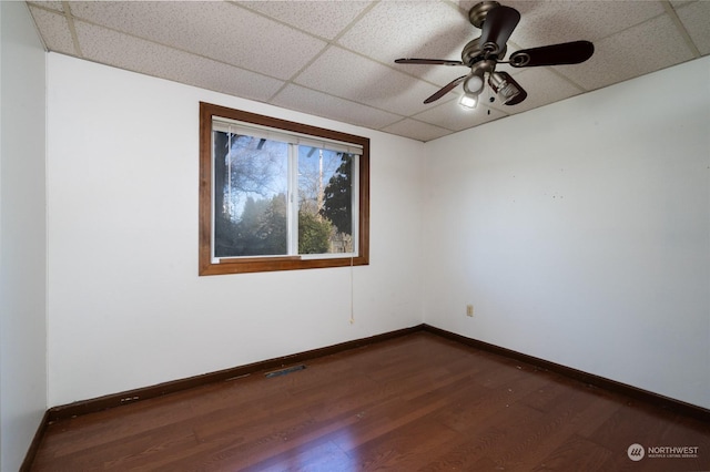 spare room featuring dark wood-type flooring, a paneled ceiling, and ceiling fan