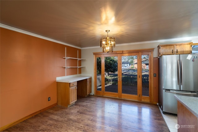 kitchen featuring stainless steel refrigerator, hanging light fixtures, ornamental molding, a notable chandelier, and light hardwood / wood-style flooring