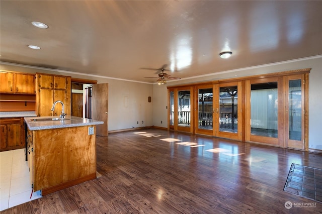 kitchen featuring sink, ornamental molding, dark hardwood / wood-style flooring, ceiling fan, and a kitchen island with sink