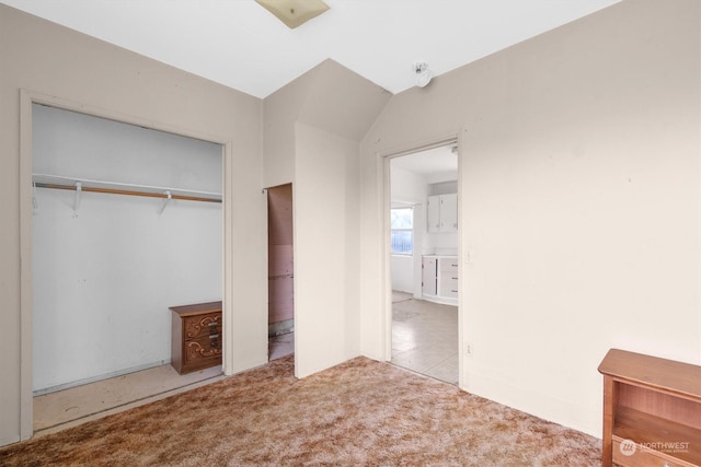 unfurnished bedroom with light colored carpet, lofted ceiling, and a closet