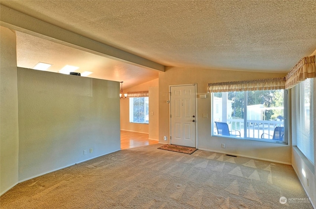 empty room featuring a chandelier, a textured ceiling, carpet, and vaulted ceiling with beams