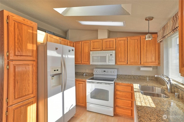 kitchen with lofted ceiling, sink, white appliances, decorative light fixtures, and light wood-type flooring