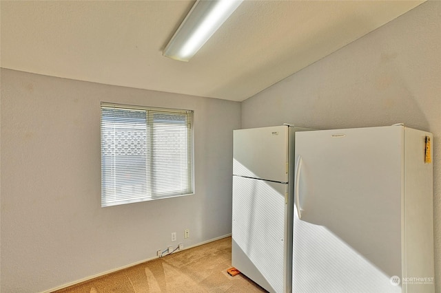 kitchen featuring white refrigerator, light colored carpet, and vaulted ceiling