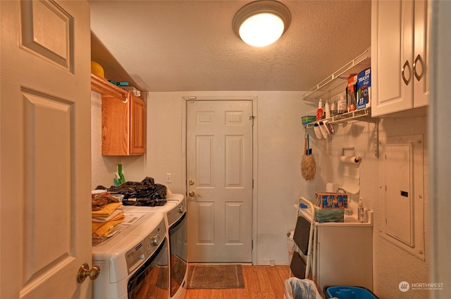 clothes washing area featuring cabinets, a textured ceiling, light hardwood / wood-style flooring, and washing machine and clothes dryer