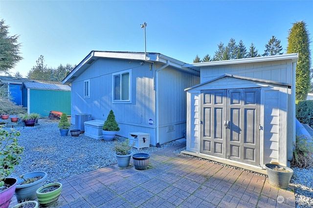 rear view of property featuring a patio and a shed