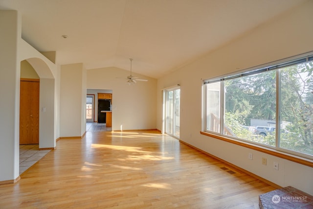 unfurnished room with ceiling fan, plenty of natural light, high vaulted ceiling, and light hardwood / wood-style flooring