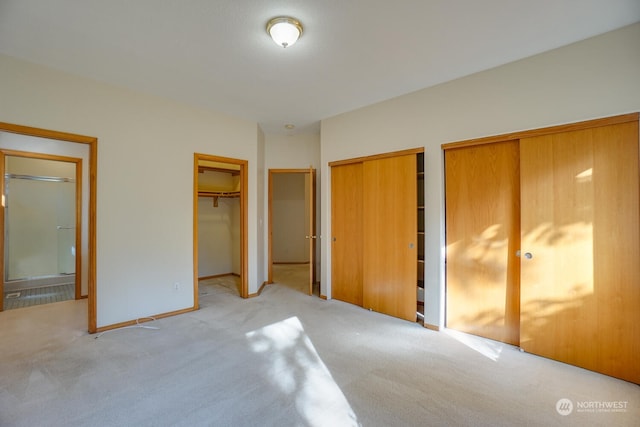 unfurnished bedroom featuring light colored carpet and two closets