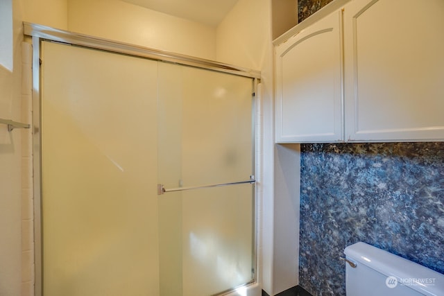 bathroom with toilet and a shower with door