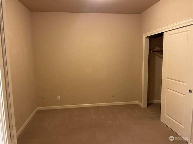 unfurnished bedroom with light colored carpet and a closet