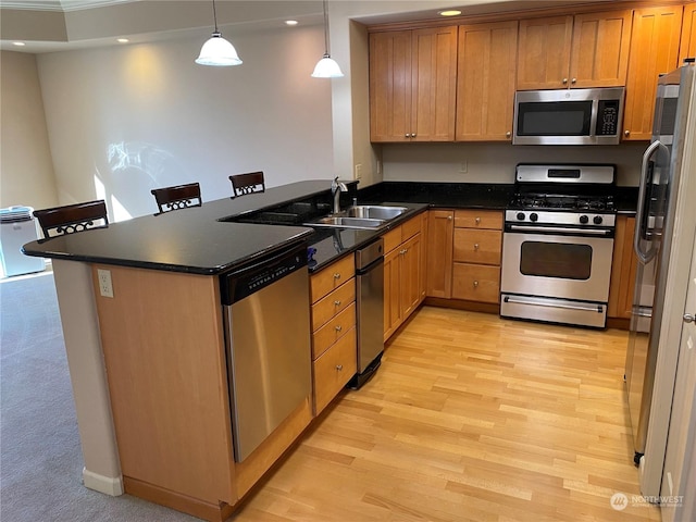 kitchen with pendant lighting, sink, a kitchen bar, kitchen peninsula, and stainless steel appliances