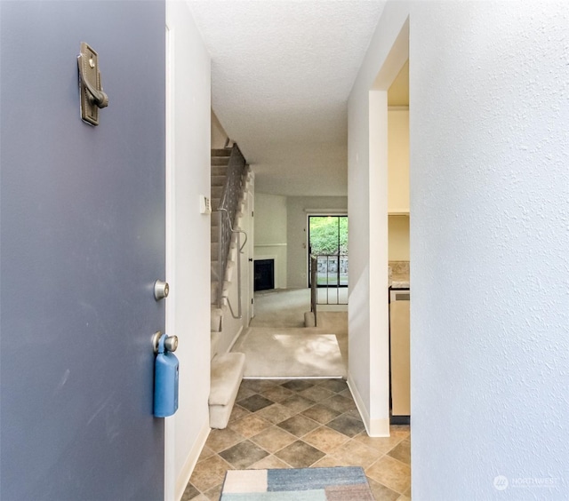 hall featuring light carpet and a textured ceiling