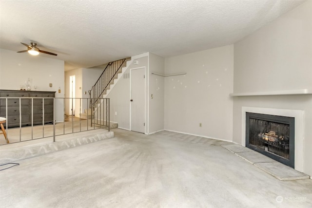 unfurnished living room featuring ceiling fan, carpet floors, and a textured ceiling