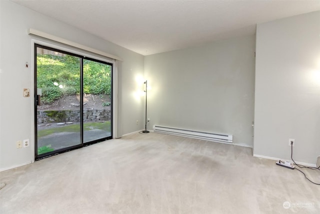 empty room featuring a baseboard heating unit and light colored carpet