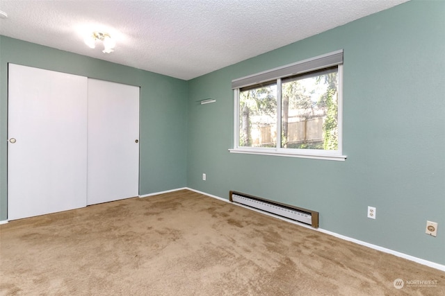 unfurnished bedroom with carpet, a textured ceiling, baseboard heating, and a closet