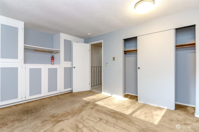 unfurnished bedroom with light colored carpet and a textured ceiling