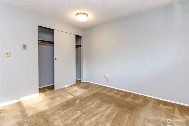 unfurnished bedroom with carpet floors, a closet, and a textured ceiling