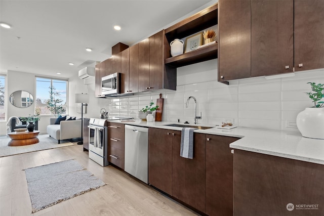 kitchen with dark brown cabinetry, light stone countertops, a wall unit AC, and appliances with stainless steel finishes