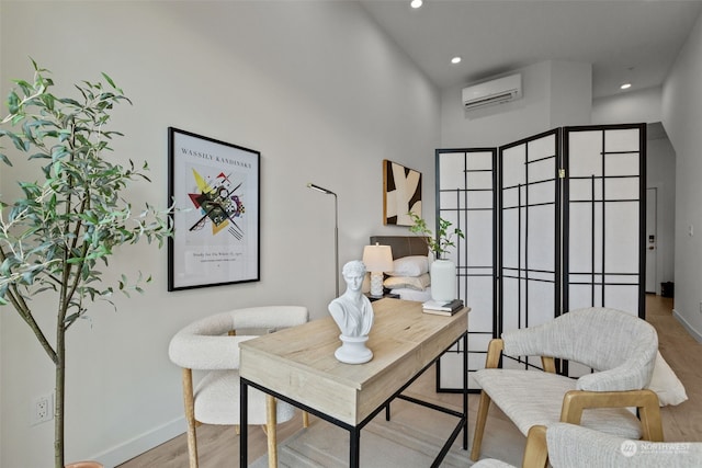 home office featuring light wood-type flooring, a high ceiling, and an AC wall unit