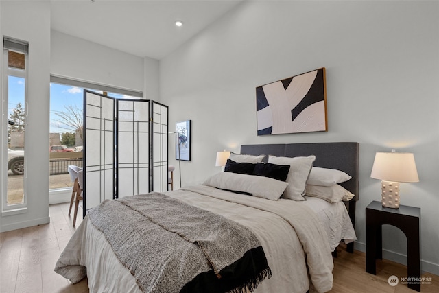 bedroom featuring a towering ceiling and light wood-type flooring