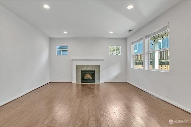 unfurnished living room featuring a tiled fireplace and wood-type flooring