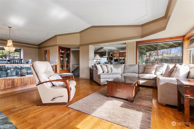 living room featuring hardwood / wood-style flooring, vaulted ceiling, and ornamental molding