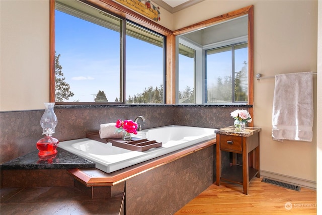 bathroom featuring hardwood / wood-style flooring and tiled bath