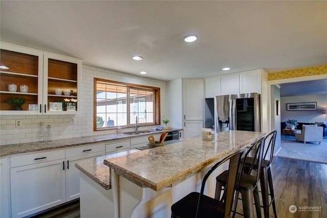 kitchen with sink, white cabinets, a kitchen breakfast bar, a center island, and stainless steel fridge with ice dispenser